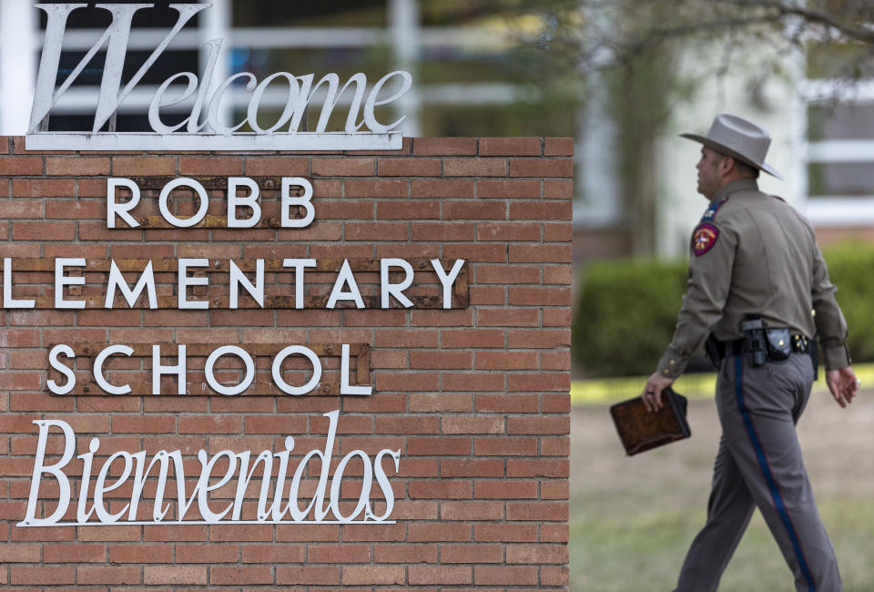 FILE - A state trooper walks past the Robb Elementary School sign in Uvalde, Texas, Tuesday, May 24, 2022, following a deadly shooting at the school. (William Luther/The San Antonio Express-News via AP, File)