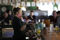 Bartender Alyssa Dooley talks with customers at Mo's Irish Pub, Tuesday, March 2, 2021, in Houston. Texas Gov. Greg Abbott announced that he is lifting business capacity limits and the state's mask mandate starting next week. (AP Photo/David J. Phillip)