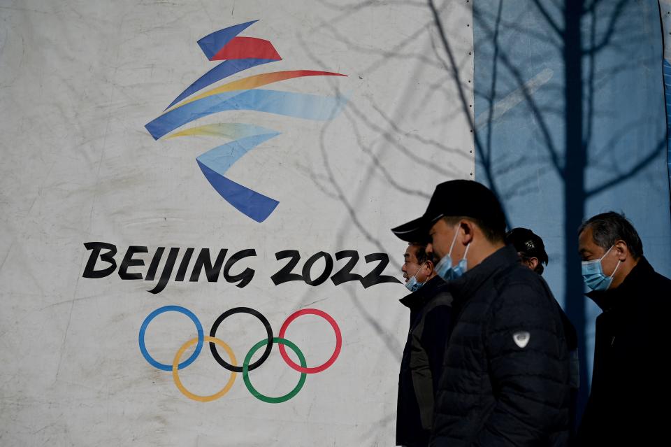 People walk past the Beijing 2022 Winter Olympics logo