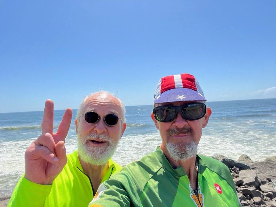 Brothers John, left, and Ed Chimahusky pose at the Pacific Ocean in Oregon on the last day of their cross-country bike trip.