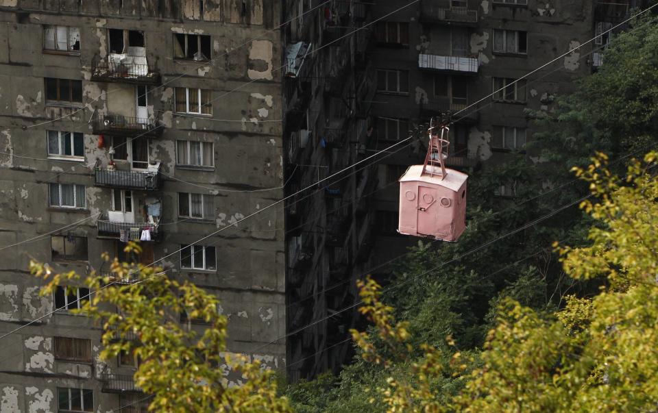 A cable car passes above apartment buildings in the town of Chiatura