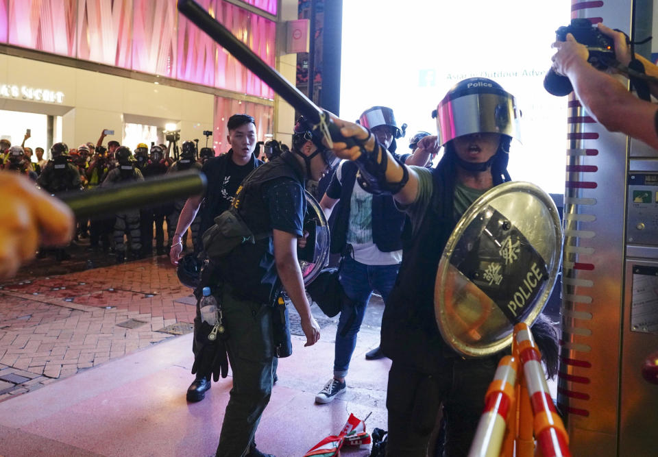 Riot police chase members of the media away in Hong Kong, Sunday, Sept. 8, 2019. Thousands of demonstrators in Hong Kong urge President Donald Trump to “liberate” the semi-autonomous Chinese territory during a peaceful march to the U.S. consulate, but violence broke out later in the business and retail district after protesters vandalized subway stations, set fires and blocked traffic. (AP Photo/Vincent Yu)