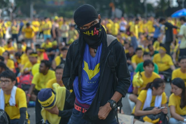 A protestor covers his face with a banner as he looks on during the second day of a demonstration demanding Prime Minister Najib Razak’s resignation and electoral reforms in Kuala Lumpur on August 30, 2015