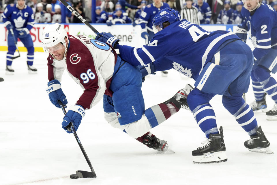 Toronto Maple Leafs defenseman Morgan Rielly (44) tries to knock Colorado Avalanche right wing Mikko Rantanen (96) off the puck during the second period of an NHL hockey game in Toronto, Saturday, Jan. 13, 2024. (Chris Young/The Canadian Press via AP)