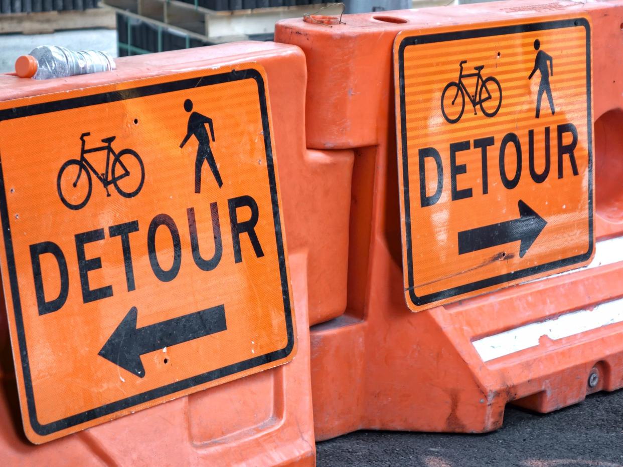 Warning signs street closed detour do not enter. road barricaded with traffic control barrels and a detour sign.