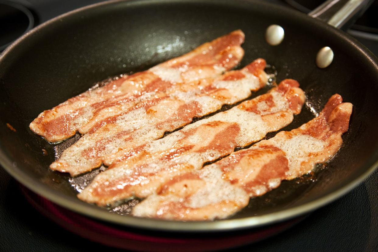 Cooking slices of healthy, low fat turkey bacon in a frying pan.  Shallow depth of field.