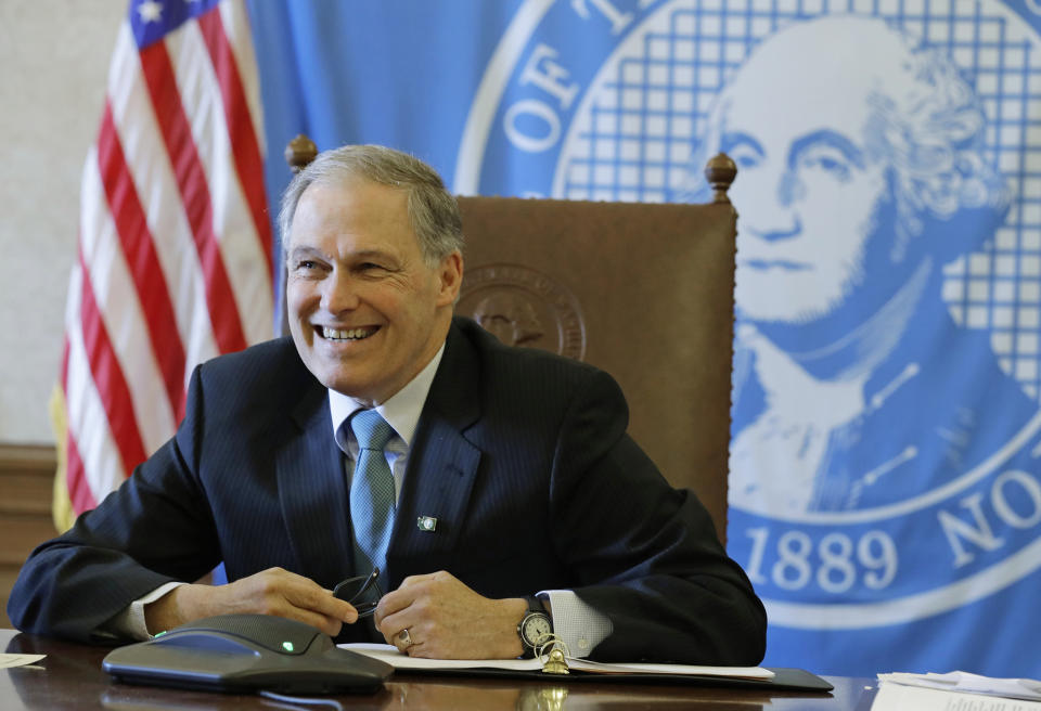 FILE - In this Wednesday, Feb. 27, 2019 file photo, Washington Gov. Jay Inslee sits in front of the state seal as he takes part in a conference call meeting with members of the AARP, at the Capitol in Olympia, Wash. Inslee's proposal for a limited public health care option cleared the state House of Representatives Friday, March 8, 2019, advancing what he has called the most practical option for expanding health coverage — and bringing to his state a national debate over what universal health care means. (AP Photo/Ted S. Warren, File)