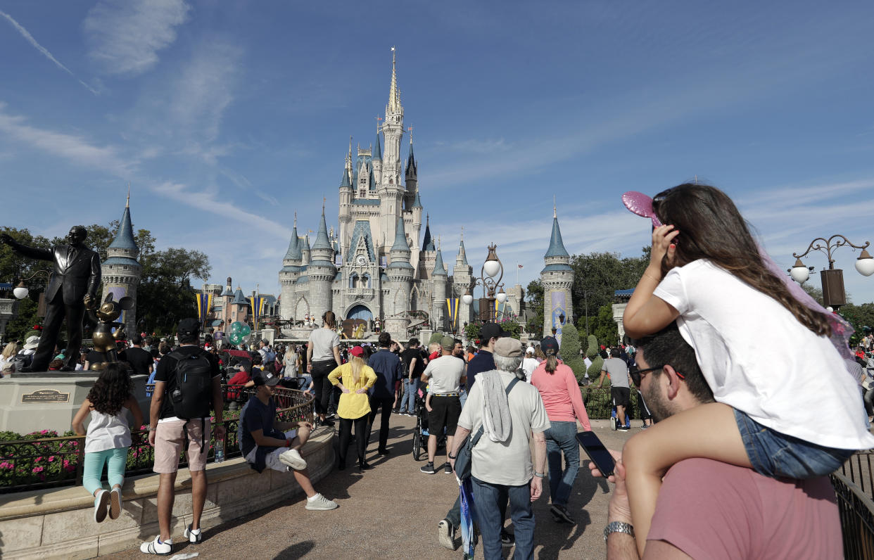 En esta foto del miércoles 9 de enero de 2019, los visitantes del parque temático caminan cerca de una estatua de Walt Disney y Mickey Mouse frente al castillo de Cenicienta en Magic Kingdom en Walt Disney World en Lake Buena Vista, Florida (AP Photo / John Raoux)