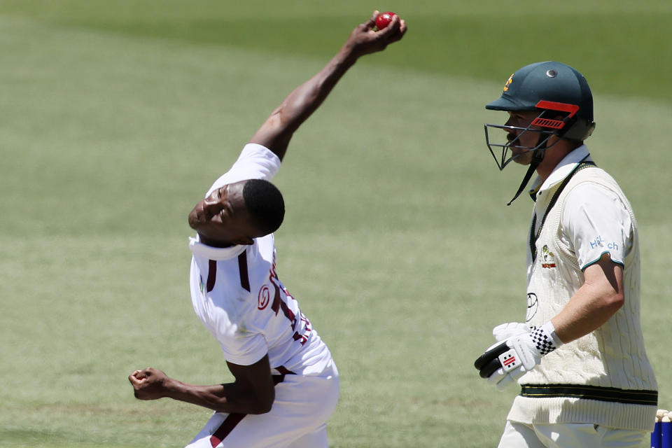 West Indies' Shamar Joseph, left, bowls as Australia's Travis Head watches on the second day of their cricket test match in Adelaide, Australia, Thursday, Jan. 18, 2024. (AP Photo/James Elsby)