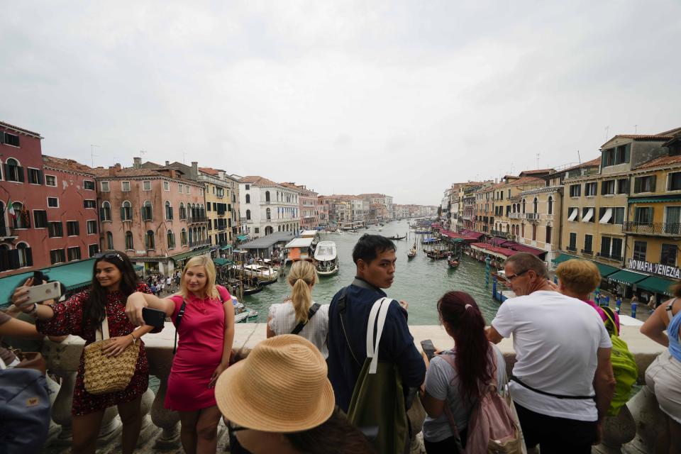 Tourists visit Rialto bridge, in Venice, Italy, Wednesday, Sept. 13, 2023. The Italian city of Venice has been struggling to manage an onslaught of tourists in the budget travel era. The stakes for the fragile lagoon city are high this week as a UNESCO committee decides whether to insert Venice on its list of endangered sites. (AP Photo/Luca Bruno)