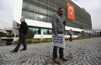 A Zaman media group journalist holds a banner as he stands outside the headquarters of Zaman daily newspaper in Istanbul December 14, 2014. REUTERS/Murad Sezer