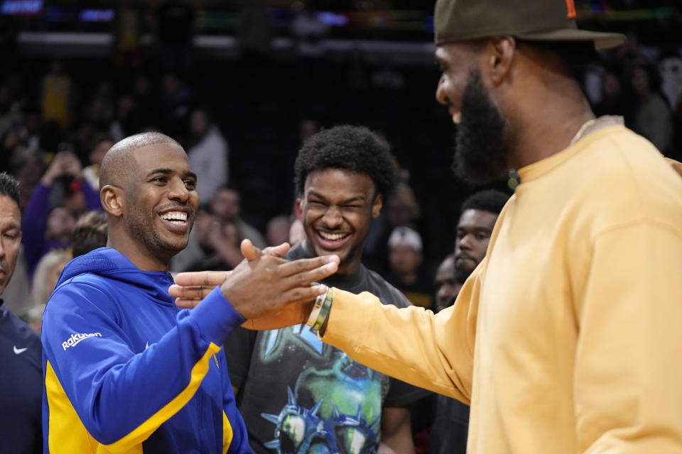 Golden State Warriors guard Chris Paul, shakes hands with Los Angeles Lakers forward LeBron James, right, as LeBron's son Bronny looks on after an NBA preseason basketball game Friday, Oct. 13, 2023, in Los Angeles. (AP Photo/Mark J. Terrill)