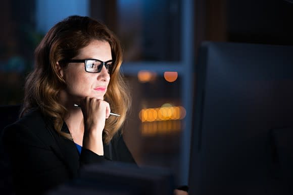 Picture of a woman at a desk looking intently at her computer screen.