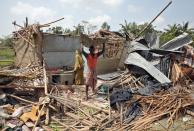 A man carries a tin sheet salvaged from the rubble of his damaged house in the aftermath of Cyclone Amphan, in South 24 Parganas district