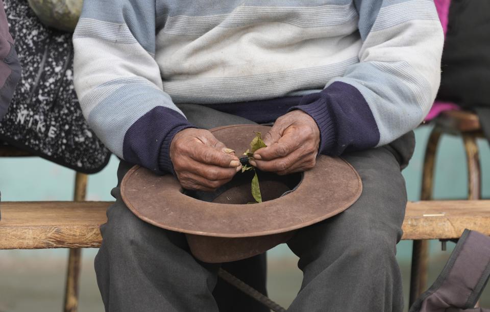 A residents holds coca leaves during a community meeting to discuss if they will get the Sinopharm COVID-19 vaccine, during a vaccine campaign set up at a local school in Mijane, Peru, Thursday, Oct. 28, 2021. While more than 55% of Peruvians have gotten at least one shot of COVID-19 vaccines, only about 25% of people in Indigenous areas have been vaccinated. (AP Photo/Martin Mejia)