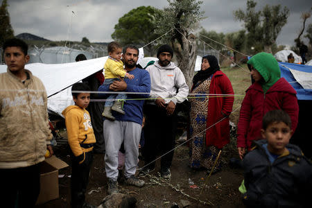 Syrian refugee Bashar Wakaa (3rd L) and his family stand in front of their tents at a makeshift camp for refugees and migrants next to the Moria camp on the island of Lesbos, Greece, November 30, 2017. REUTERS/Alkis Konstantinidis