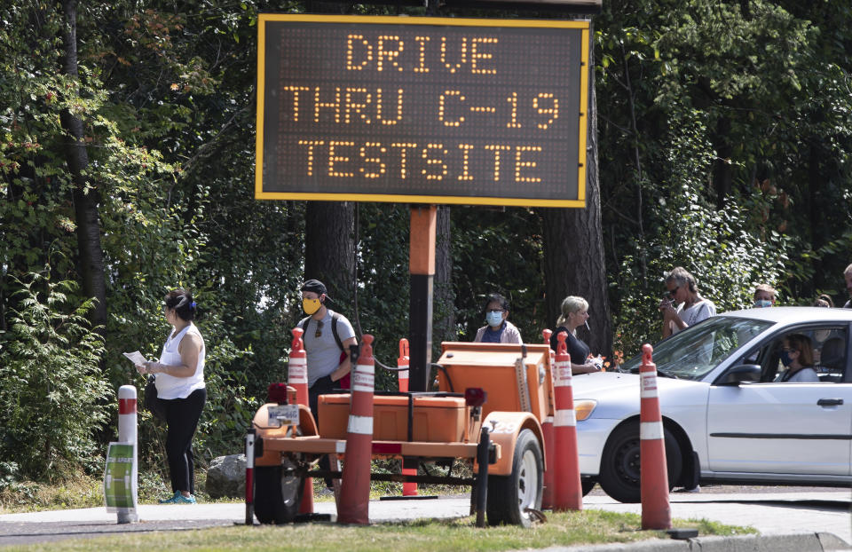 People wait in line at a COVID-19 testing facility during the coronavirus pandemic in Burnaby, British Columbia, on Thursday, Aug. 13, 2020. (Darryl Dyck/The Canadian Press via AP)