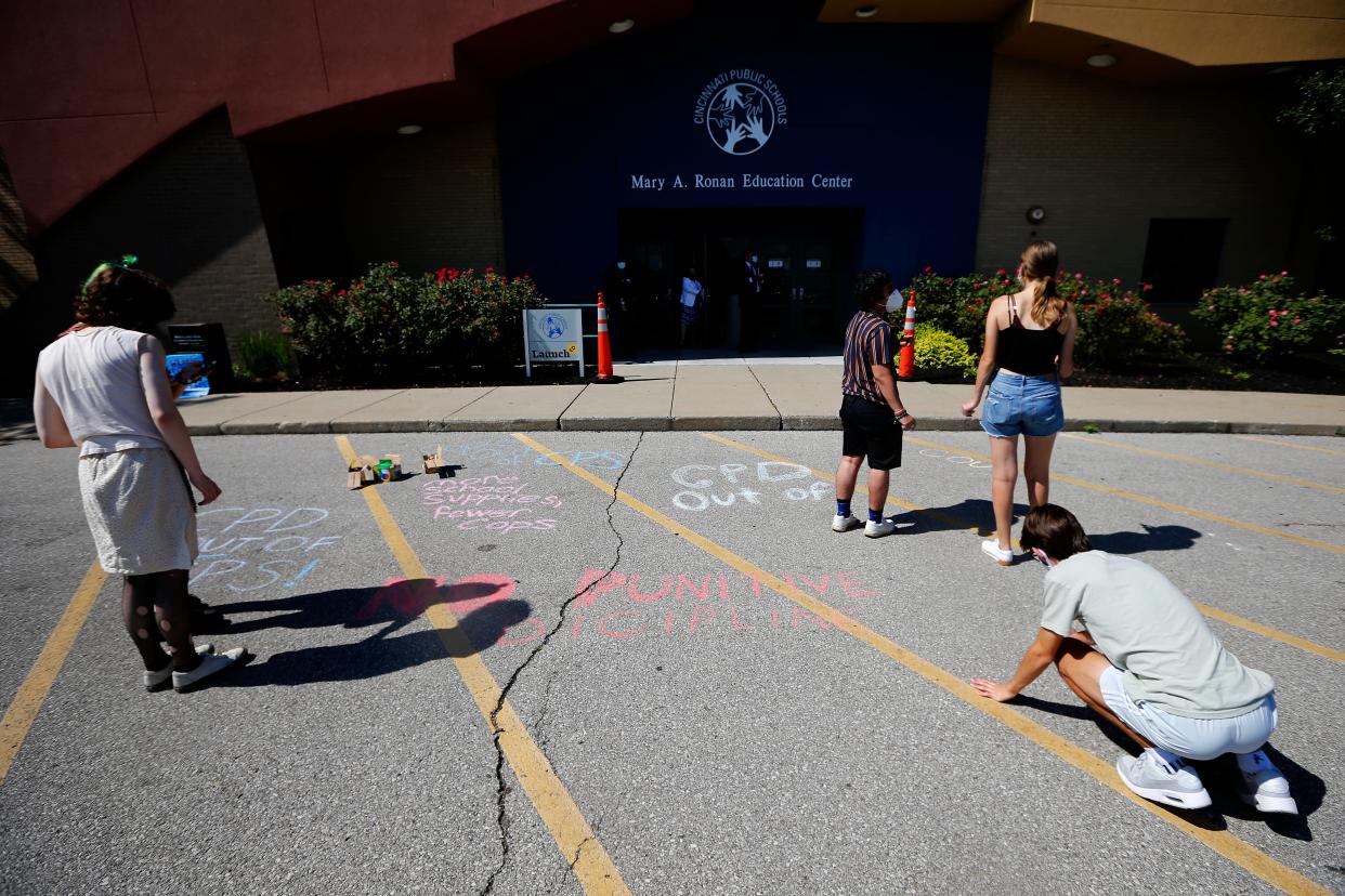 Student write messages on the pavement outside of the Cincinnati Public Schools administrative building in the Corryville neighborhood of Cincinnati on Monday, June 28, 2021. The Young Activists Coalition hosted a barbecue and protest outside of meeting to push for the removal of Cincinnati Police officers from the public schools.