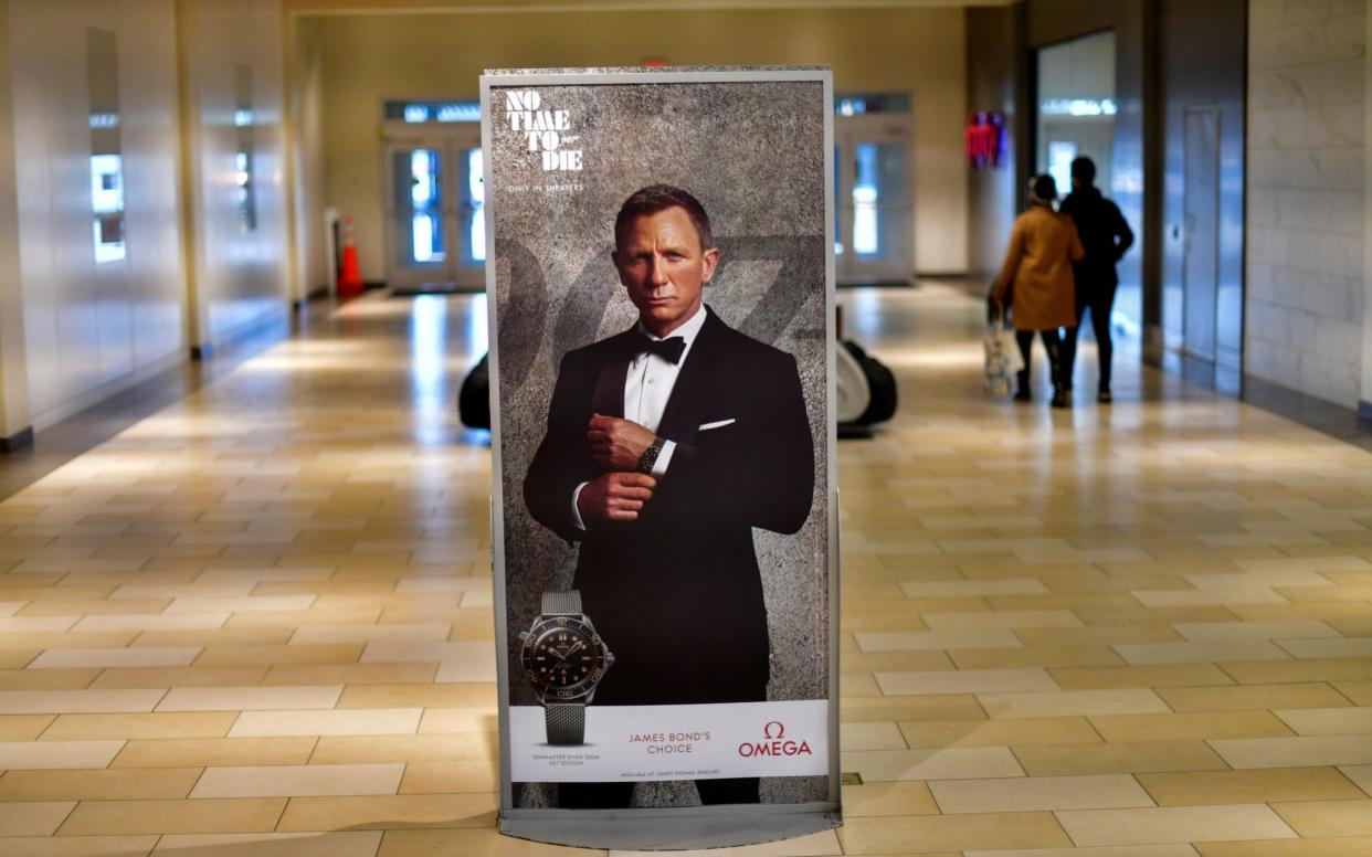 Shoppers walk past an advertisement for the upcoming James Bond film "No Time To Die" - Reuters