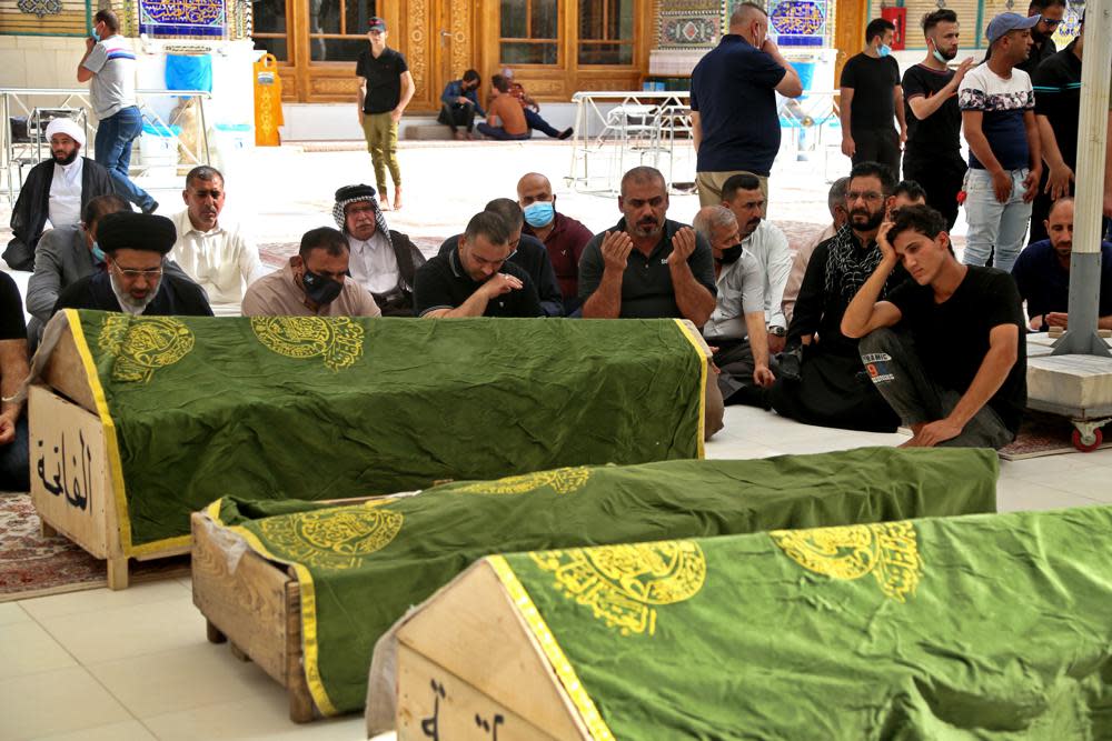 Mourners pray near the coffins of coronavirus patients that were killed in a hospital fire, during their funeral at the Imam Ali shrine in Najaf, Iraq, Sunday, April 25, 2021. (AP Photo/Anmar Khalil)