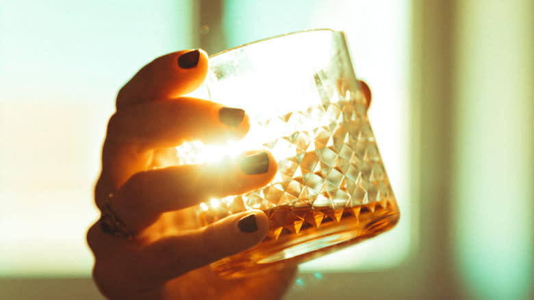 hand holding glass of bourbon