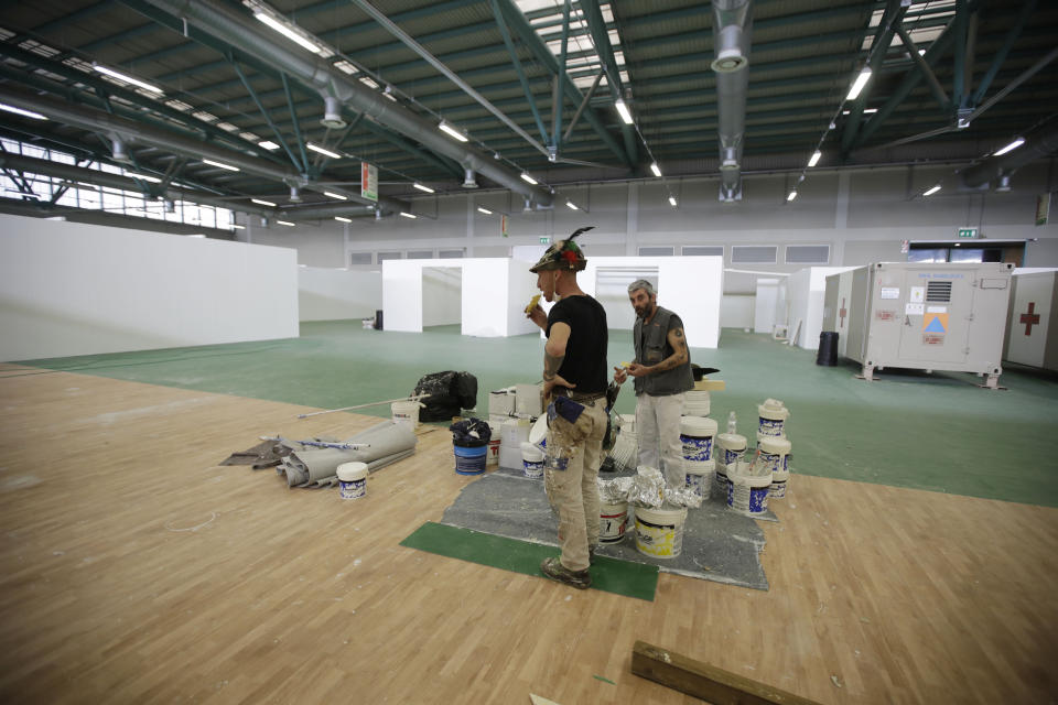 FILE - In this March 26, 2020 file photo, Italian Army Alpini corps take a break as they prepare a new hospital in the spaces of the Bergamo Fair, in Bergamo Italy. Italy is seeing a slight stabilizing in its confirmed coronavirus infections two weeks into the world’s most extreme nationwide shutdown, but the virus is taking its silent spread south after having ravaged the health care system in the north. The new coronavirus causes mild or moderate symptoms for most people, but for some, especially older adults and people with existing health problems, it can cause more severe illness or death. (AP Photo/Luca Bruno, file)