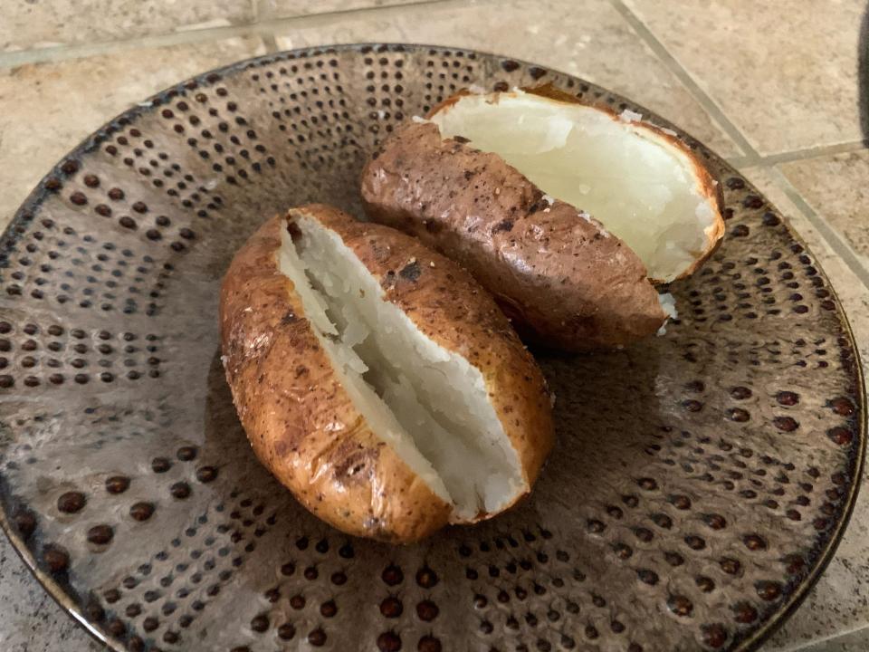 Two potatoes cut open on a brown plate