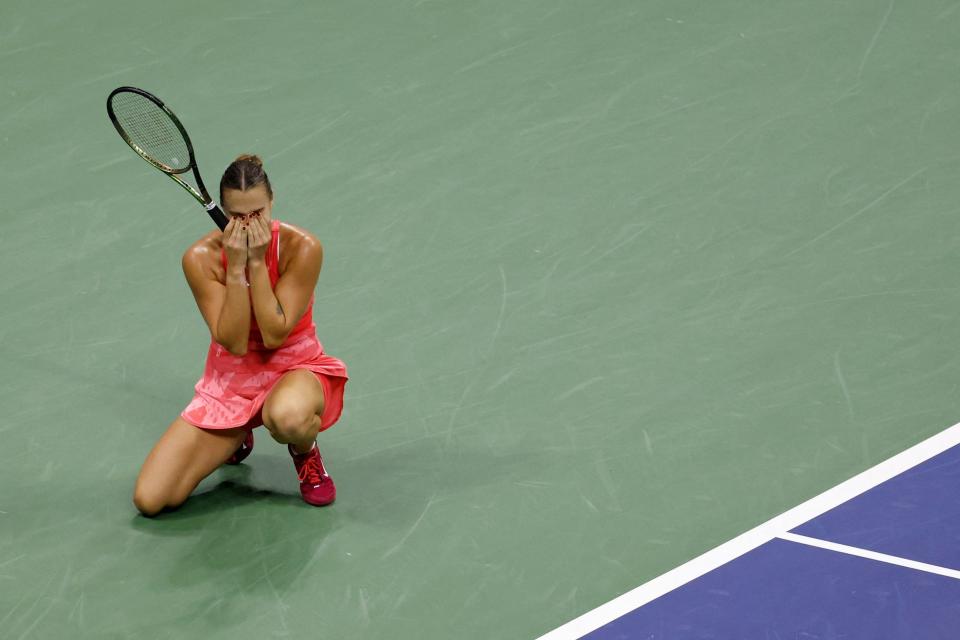 Aryna Sabalenka drops to her knees and places her head in her hands in celebration.