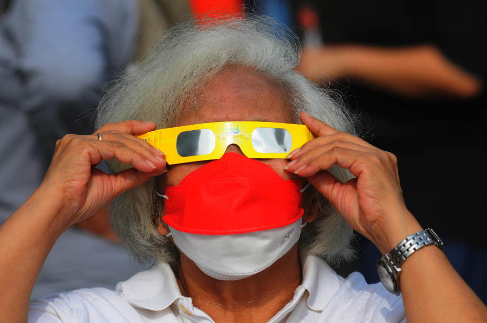 A person wears protective glasses to watch a partial hybrid solar eclipse at Ismail Marzuki Park in Jakarta, Indonesia on April 20, 2023. The hybrid solar eclipse is a unique type of solar eclipse that experiences two phases simultaneously, namely the ring phase and the total phase. (Photo by Eko Siswono Toyudho/Anadolu Agency via Getty Images)