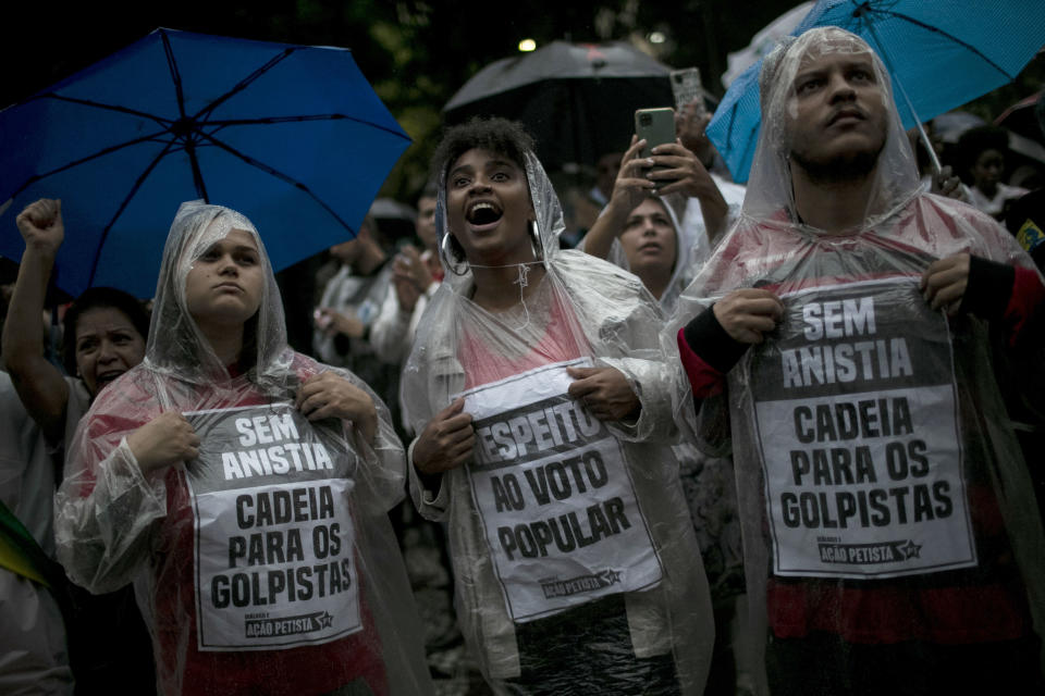 Protesters hold signs that read in Portuguese "Without anesthesia. Jail for coup plotters" and "Respect the popular vote" during an act in favor of Brazilian democracy in Rio de Janeiro, Brazil, Monday, Jan. 9, 2023, one day after supporters of former President Jair Bolsonaro stormed government buildings in the capital city of Brasilia. (AP Photo/Bruna Prado)