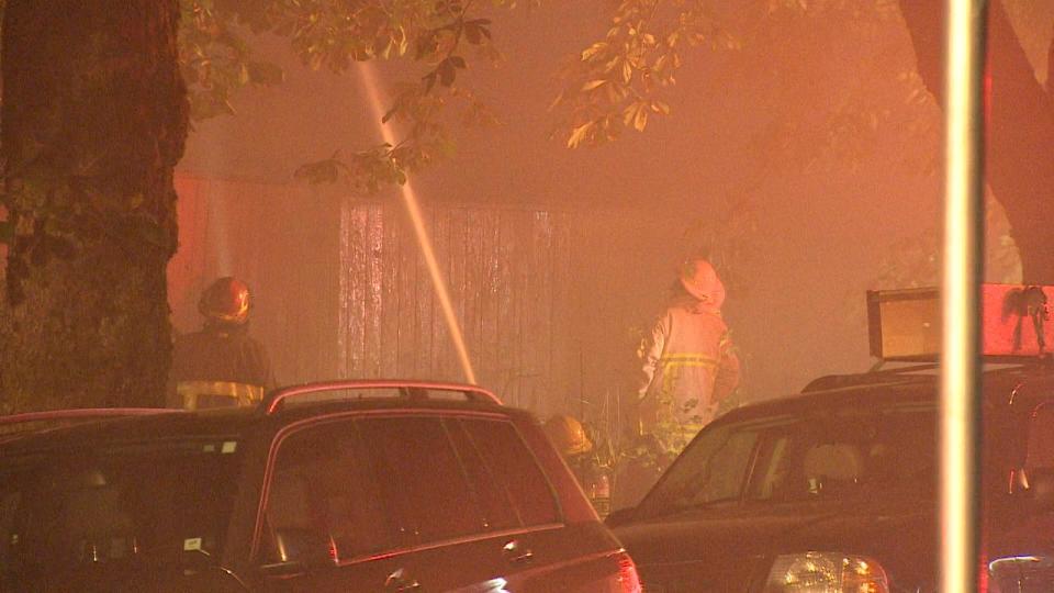 Firefighters hose down an apartment building in Vancouver's Mount Pleasant neighbourhood during a fire on July 27, 2023.