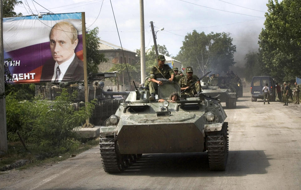FILE - Ossetian soldiers on top of an armored personnel carrier enter Tskhinvali, the capital of Georgian breakaway enclave of South Ossetia on Aug. 11, 2008, next to a giant portrait of Prime Minister Vladimir Putin and inscription in Cyrillic: Putin is our President. Russia fights a short war with Georgia, gaining full control of the separatist Abkhazia and South Ossetia regions. (AP Photo/Mikhail Metzel, File)
