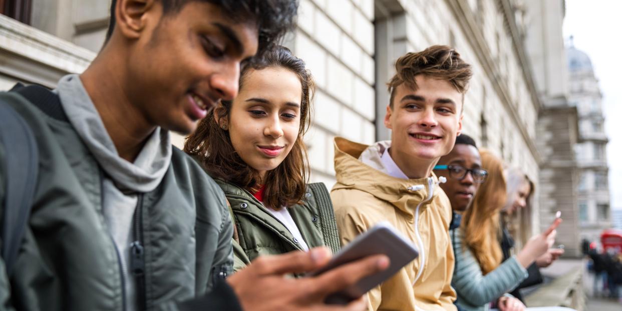 Teenagers looking at a phone.