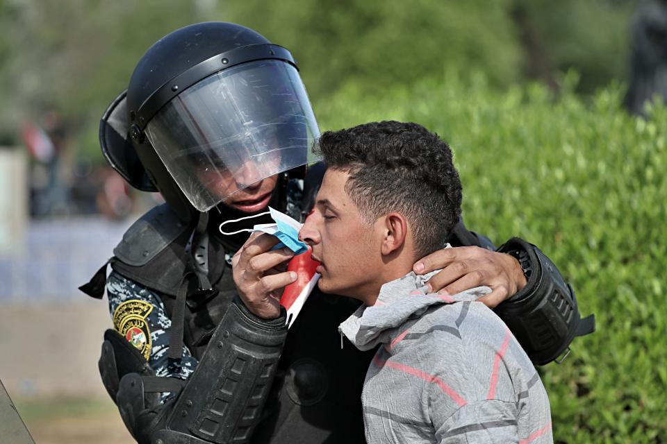 A policeman in the riot force performs first aid to a wounded protester during a demonstration in central Baghdad, Iraq, Friday, Oct. 25, 2019. Iraqi police fired live shots into the air as well as rubber bullets and dozens of tear gas canisters on Friday to disperse thousands of protesters on the streets of Baghdad, sending young demonstrators running for cover and enveloping a main bridge in the capital with thick white smoke. (AP Photo/Hadi Mizban)