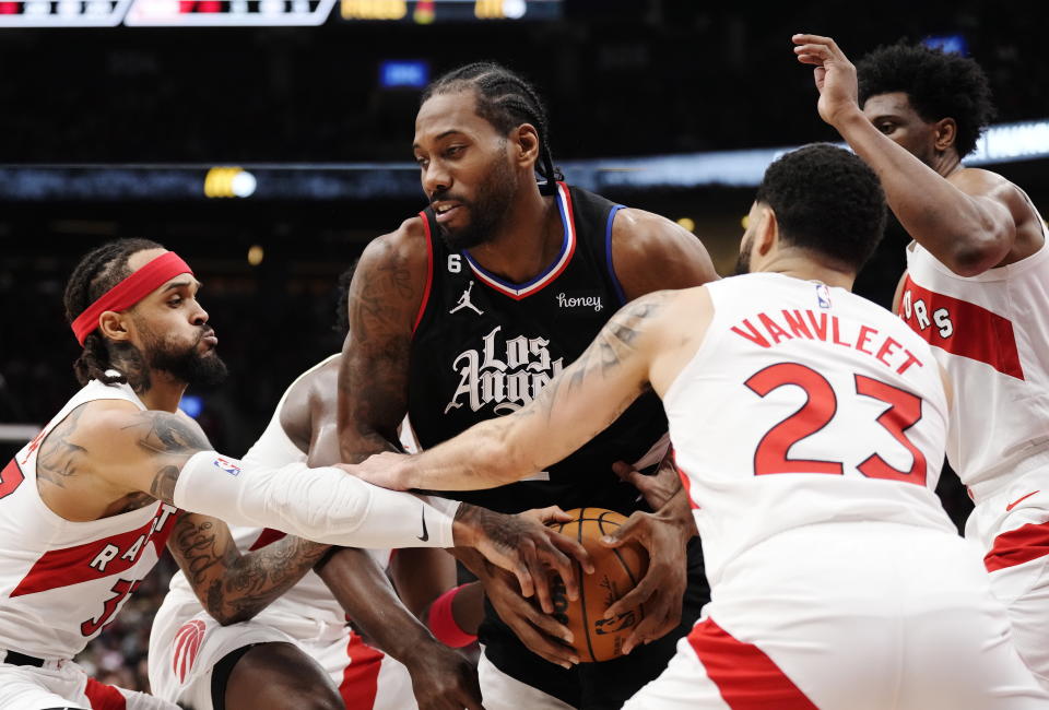 Los Angeles Clippers forward Kawhi Leonard tries to keep the ball from Toronto Raptors guard Gary Trent Jr., left, and guard Fred VanVleet (23) during the first half of an NBA basketball game Tuesday, Dec. 27, 2022, in Toronto. (Frank Gunn/The Canadian Press via AP)