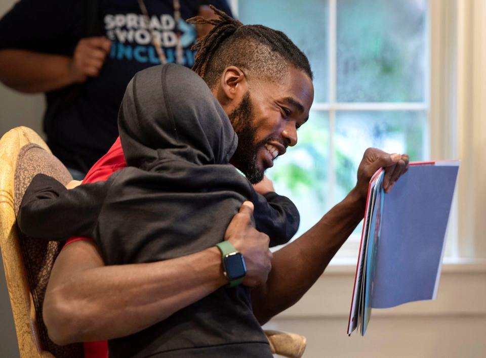 Literacy advocate Oliver James gets a hug from Gove Elementary student Brian Smith, 8, as he reads I Am Every Good Thing by Derrick Barnes November 14, 2023 during Literacy Day at Ann Norton Sculpture Gardens in West Palm Beach.