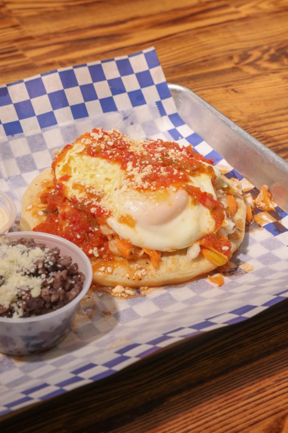 A pupusa on a blue-and-white-paper-lined metal tray