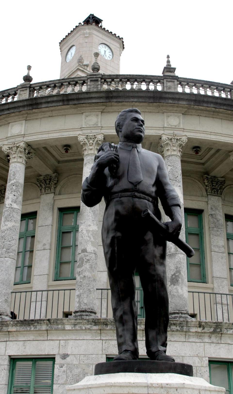 A statue of Coral Gables founder George Merrick holding a roll of building plans, by sculptor William Beckwith, stands outside Coral Gables City Hall.