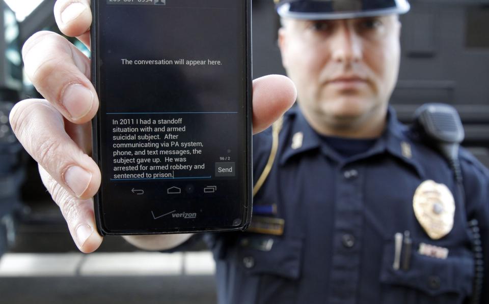 In a May 6, 2014 photo, Sgt. Andres Wells of the Kalamazoo Deptartment of Public Safety, who successfully used text messaging to negotiate with a suicidal robbery suspect during a 2011 standoff, shows his phone. With 6 billion text messages exchanged daily in the United States, texting is becoming a more frequent part of police crisis negotiations. (AP Photo/Mark Bugnaski)