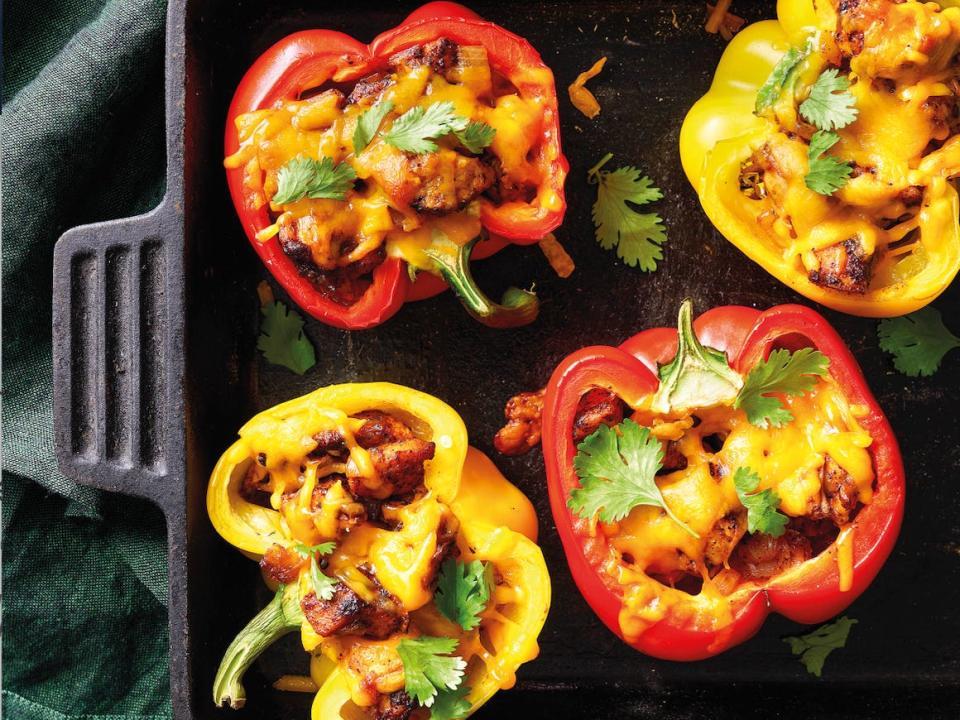 A black skillet with four stuffed bell peppers, seen from a bird's eye view.