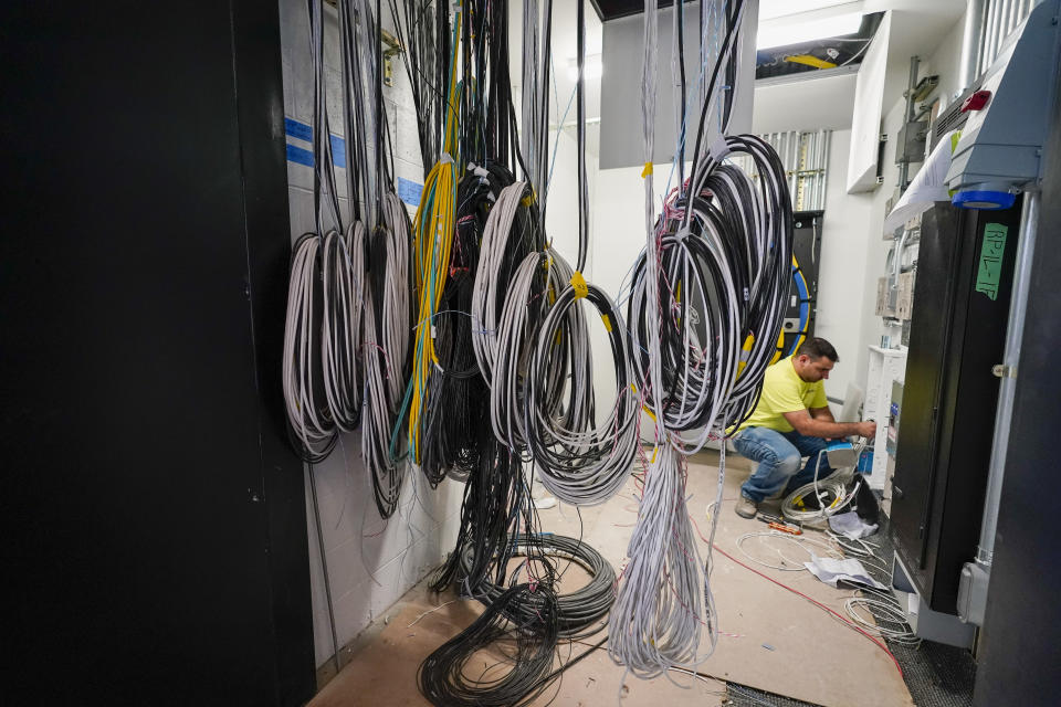 An electrician works on the wiring that will power and control the Hauser Digital Wall which will live stream performances from inside the hall into the lobby at the the newly renovated David Geffen Hall, Thursday, Aug. 25, 2022, at the Lincoln Center for the Performing Arts in New York. After a $550 million renovation that took two years, the New York Philharmonic returns to David Geffen Hall for a series of openings beginning with a Thursday night ribbon-cutting, a Friday performance for construction workers and Saturday afternoon and evening community concerts. (AP Photo/Mary Altaffer)