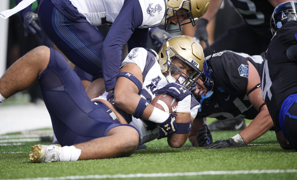 Navy defensive end Justin Reed, left, recovers a fumble by Air Force quarterback Haaziq Daniels, right, as guard Luke Hallstrom, top, reaches in during the first half of an NCAA college football game Saturday, Oct. 1, 2022, at Air Force Academy, Colo. (AP Photo/David Zalubowski)