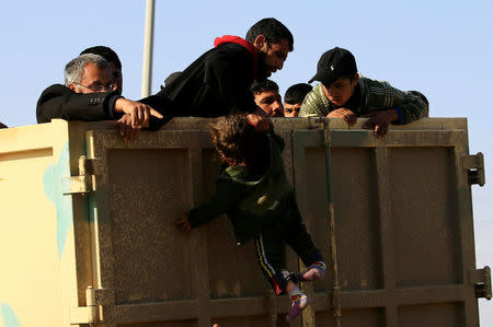 A displaced Iraqi man, who fled his home during a battle between Iraqi forces and Islamic State militants, pulls his child into a vehicle in Mosul, Iraq March 9, 2017. REUTERS/Thaier Al-Sudani