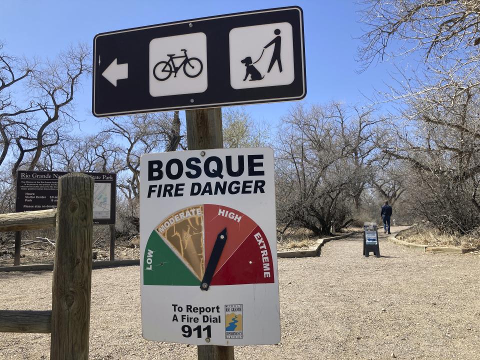 A visitor walks down at path beyond a fire danger sign at the Rio Grande Nature Center State Park in Albuquerque, N.M., Wednesday, March 29, 2023. New Mexico fire managers and land managers warned about the potential for another busy wildfire season as vegetation begins to dry out and spring winds kick up. (AP Photo/Susan Montoya Bryan)
