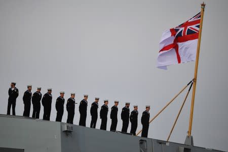Sailors stand to attention on board HMS Queen Elizabeth, as they wait for the MV Boudicca to leave the harbour in Portsmouth