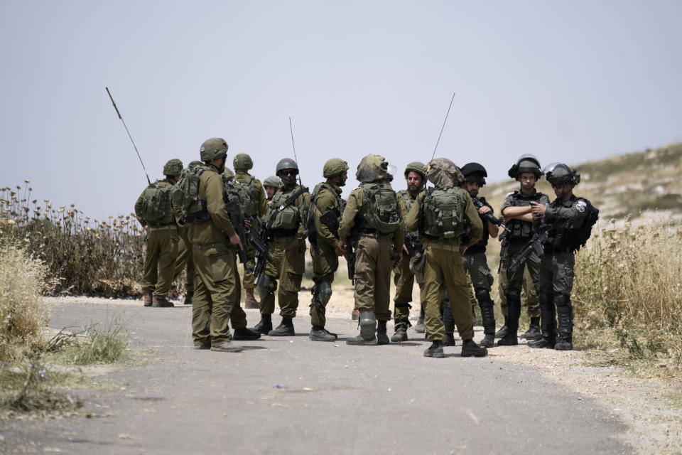 Israeli soldiers and Border Police are deployed at the site where Israeli settlers burned Palestinian cars and wheat fields in the village of al-Mughayyir near the West Bank city of Ramallah, Friday, May 26, 2023. Jewish settlers attacked Palestinian farmers and torched five vehicles in the village, the official Palestinian news agency reported. It added that five farmers were injured when settlers beat them. There was no immediate comment from the Israeli military.(AP Photo/Majdi Mohammed)