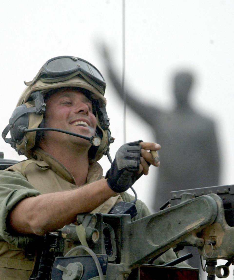 FILE - In this April 9, 2003 file photo, Staff Sgt. Nick Popaditch of the 3rd Battalion, 4th Marines Regiment, smokes a cigar while standing on top of his tank, as he arrives at a main crossroad in downtown Baghdad. A statue of then Iraqi President Saddam Hussein is in the background. On April 7, 2004, while serving as a United States Marine in Iraq, Popaditch's tank was struck by an RPG, with shrapnel carving a path through his sinuses and destroying his right eye. His actions earned him a Silver Star and a Purple Heart but cost him his military career. (AP Photo/Laurent Rebours)