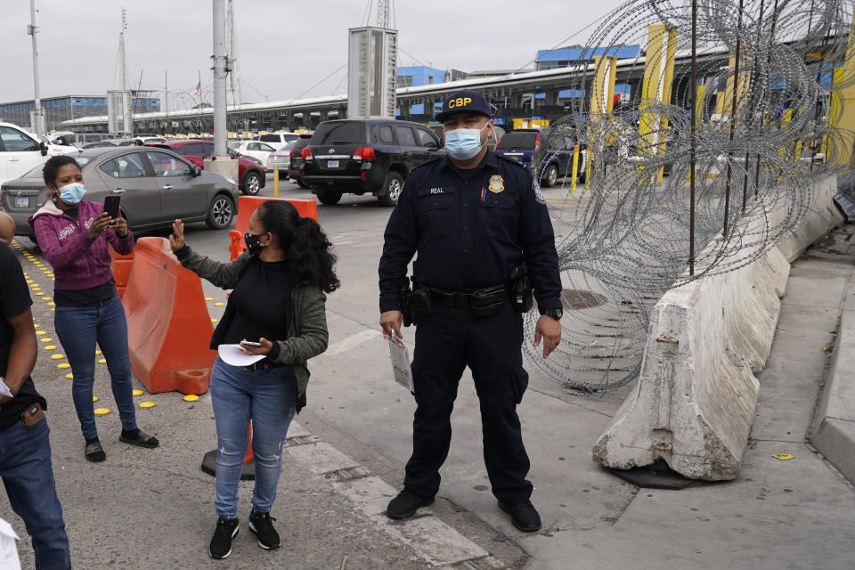 Lizeth Morales, of Honduras, waves to a friend as she crosses into the United States to begin the asylum process Monday, July 5, 2021, in Tijuana, Mexico. Dozens of people are allowed into the U.S. twice a day at a San Diego border crossing, part of a system that the Biden administration cobbled together to start opening back up the asylum system in the U.S. Immigration advocates have been tasked with choosing which migrants can apply for a limited number of slots to claim humanitarian protection. (AP Photo/Gregory Bull)