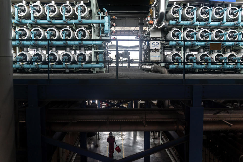 A worker passes under the reverse osmosis membranes on display at the NEWater visitor Center in Singapore, Tuesday, July 18, 2023. During this process, water passes through semi-permeable membranes to separate out bacteria and other undesirable contaminants. (AP Photo/David Goldman)