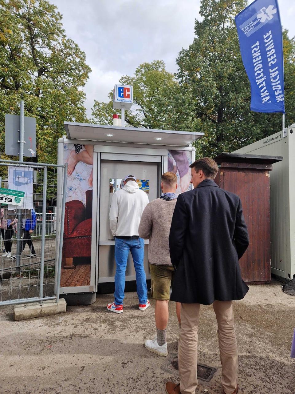 ATM at Oktoberfest with three men waiting to withdraw